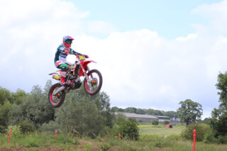 A motocross rider jumps high on a dirt bike, showcasing the energy and excitement of the sport.