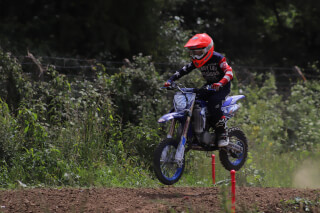 A motocross rider is airborne on a dirt bike during a race, captured in a dynamic action shot.