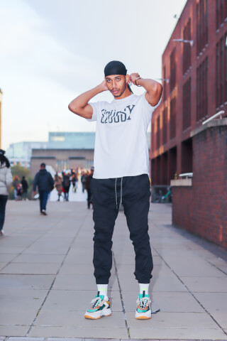 A stylish man in streetwear poses confidently on a city street, perfect for urban fashion and lifestyle campaigns.