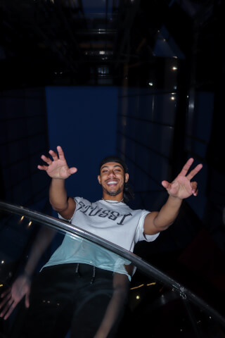 Smiling man posing in Stussy t-shirt in a modern urban building.