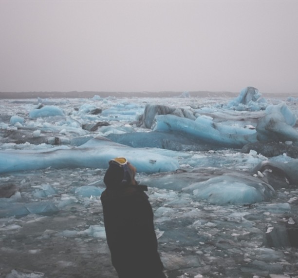 A person looks out at the icebergs floating in the Jökulsárlón glacial lagoon in Iceland on a misty day.