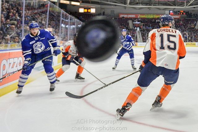 Action shot of hockey players on the ice during a game with the puck in motion.