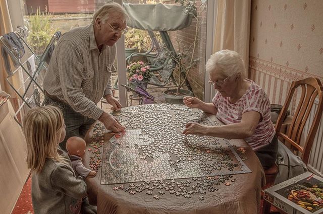 A family enjoys a quiet moment together doing a jigsaw puzzle at home, creating a warm and loving scene.