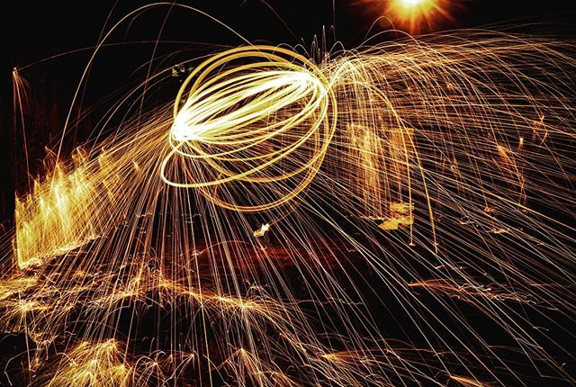 Abstract light painting with sparks and trails creates a dynamic and mysterious visual effect in the darkness.