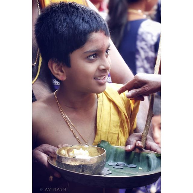 A smiling Indian boy with a gold chain attends a traditional ceremony.