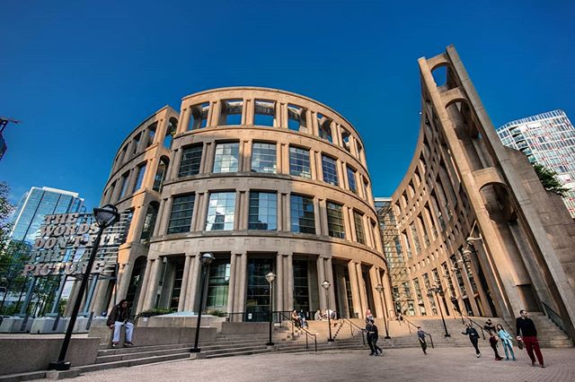 The Vancouver Public Library stands tall, a modern architectural marvel, with people walking around its plaza.