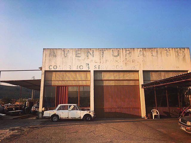 An old auto repair shop with a vintage car parked outside, capturing a sense of nostalgia and abandonment.