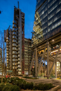 A modern cityscape showcases architectural marvels in London's financial district under a twilight sky.