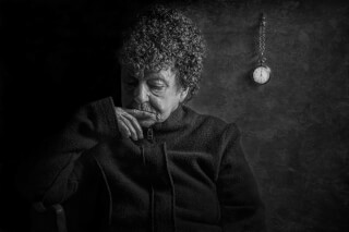 A monochrome portrait of an elderly woman in thought, with a vintage pocket watch emphasizing the passage of time.
