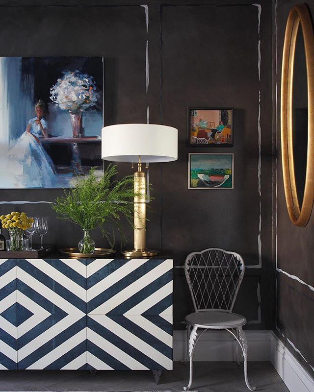 A stylish interior featuring art, a patterned sideboard, lamp and chair. Sophisticated home decor.