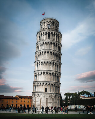 The Leaning Tower of Pisa rises against a blue sky, a famous Italian landmark attracting tourists from around the globe.