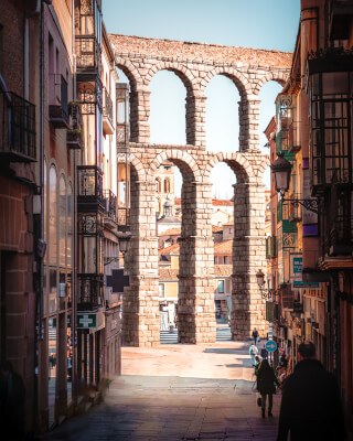 The ancient Roman aqueduct of Segovia, Spain, stands tall amidst a charming street with historic buildings.
