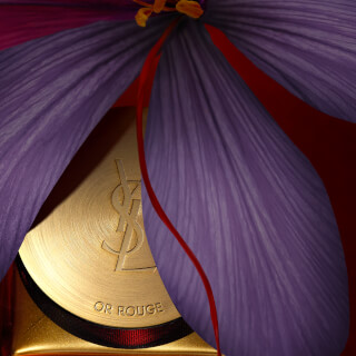 Close-up of Yves Saint Laurent Or Rouge cream with a purple flower, ideal for luxury skincare campaigns.