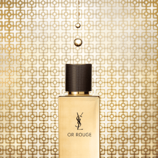 A luxurious Yves Saint Laurent Or Rouge perfume bottle with liquid droplets on a gold patterned background.